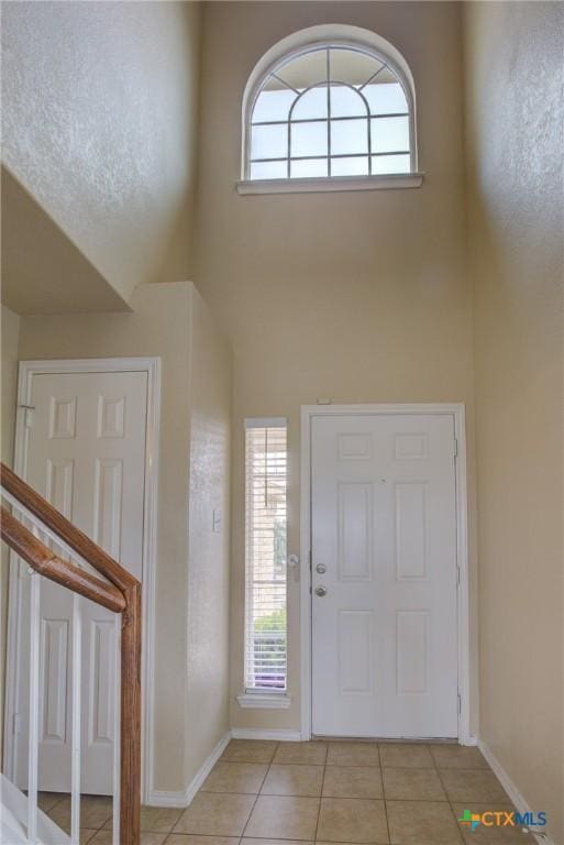 entryway featuring light tile patterned flooring, a healthy amount of sunlight, and a high ceiling