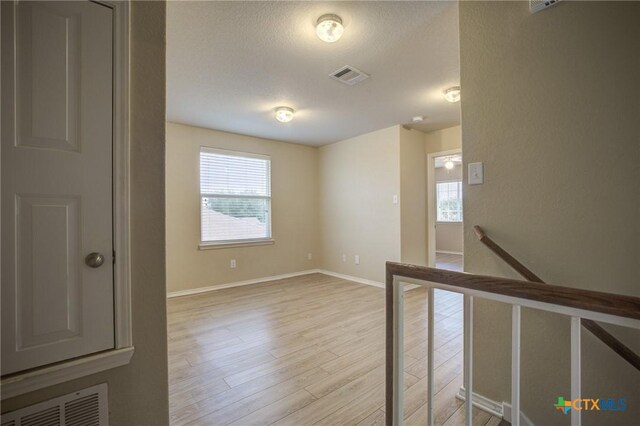 unfurnished room featuring a textured ceiling and light wood-type flooring