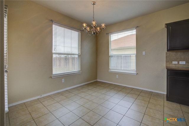 unfurnished dining area with light tile patterned floors and a notable chandelier