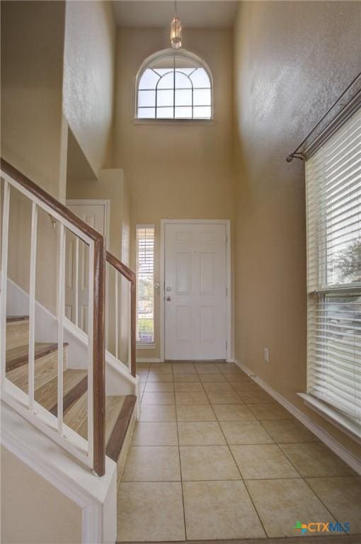 entryway featuring a high ceiling and light tile patterned floors