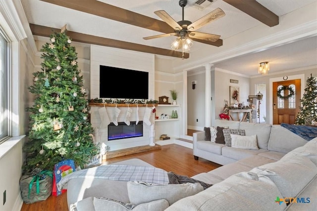 living room featuring ornamental molding, ceiling fan, beamed ceiling, a fireplace, and hardwood / wood-style floors