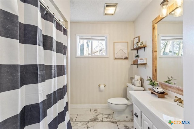 bathroom featuring vanity, a textured ceiling, toilet, and a healthy amount of sunlight