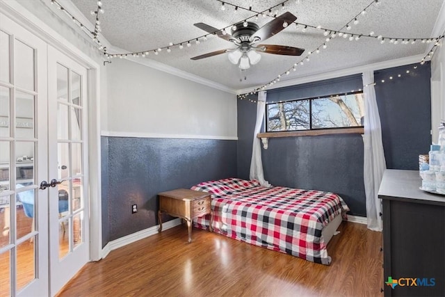 bedroom with french doors, a textured ceiling, ceiling fan, crown molding, and hardwood / wood-style flooring