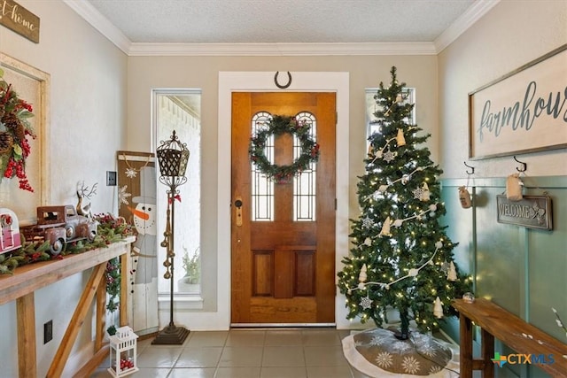 tiled entryway featuring crown molding and a textured ceiling