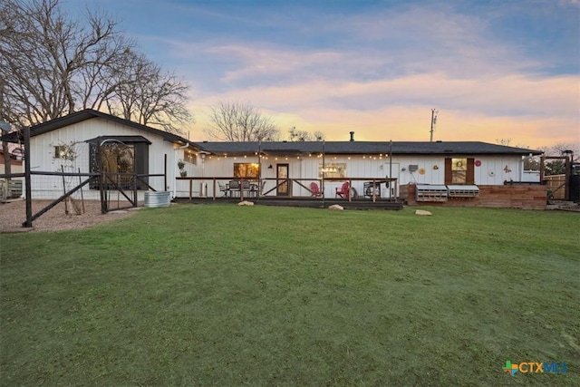 back house at dusk featuring a lawn