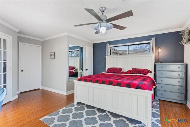 bedroom with hardwood / wood-style floors, a textured ceiling, ceiling fan, and crown molding