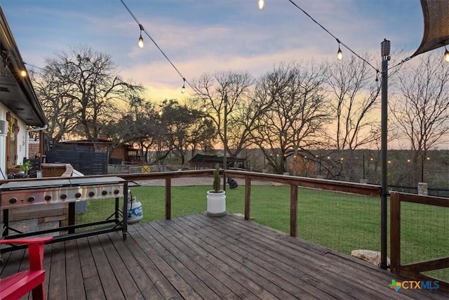 deck at dusk featuring a lawn