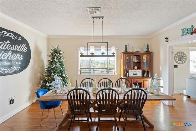 dining area featuring hardwood / wood-style floors, a textured ceiling, and crown molding