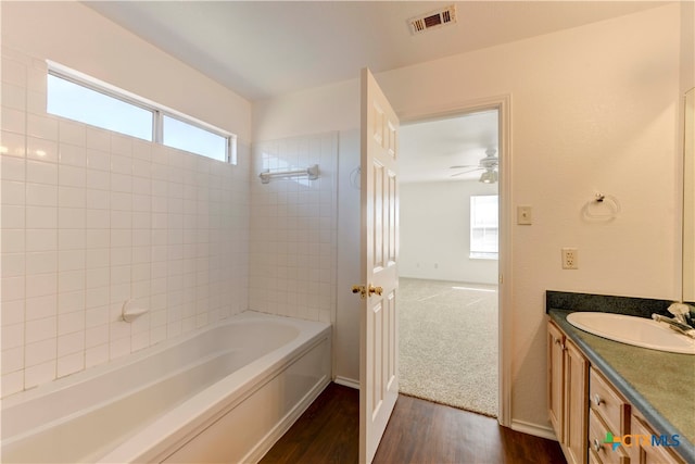 bathroom with wood-type flooring, vanity, and tiled shower / bath