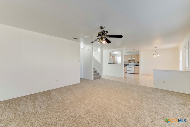 unfurnished living room featuring light carpet and ceiling fan with notable chandelier