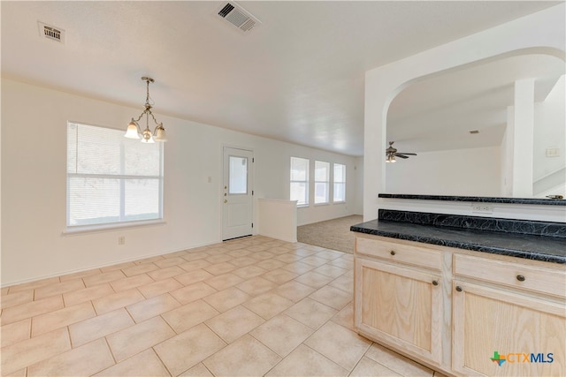 kitchen with plenty of natural light, hanging light fixtures, ceiling fan with notable chandelier, and light brown cabinets