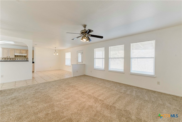 unfurnished living room with ceiling fan with notable chandelier and light tile patterned floors