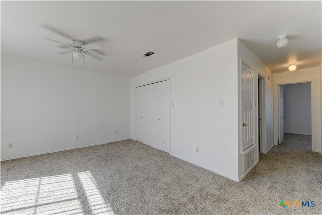 unfurnished bedroom with light carpet, a closet, and ceiling fan