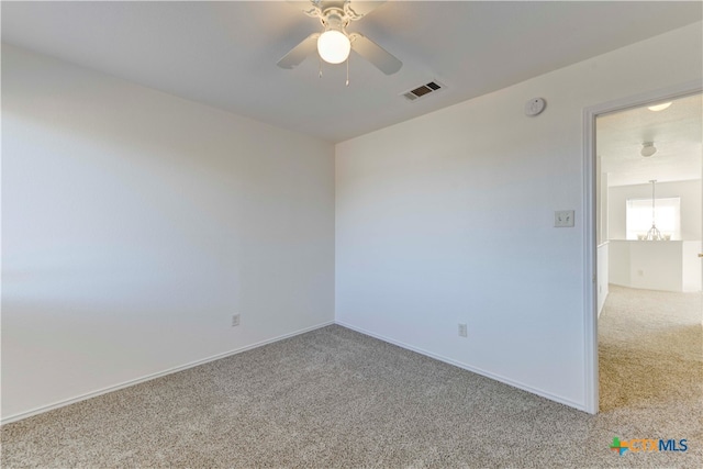 empty room featuring ceiling fan with notable chandelier and carpet floors