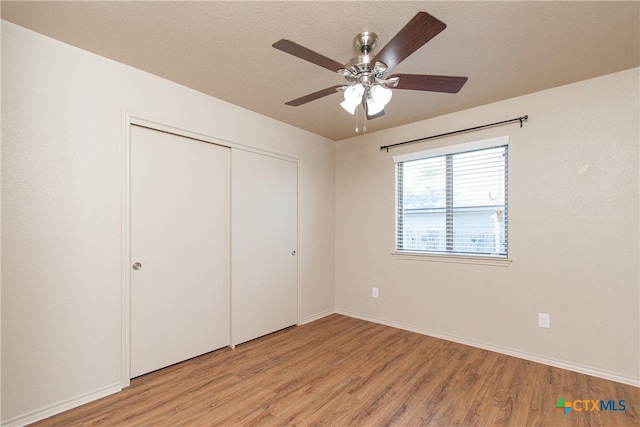 unfurnished bedroom with a textured ceiling, light hardwood / wood-style flooring, ceiling fan, and a closet