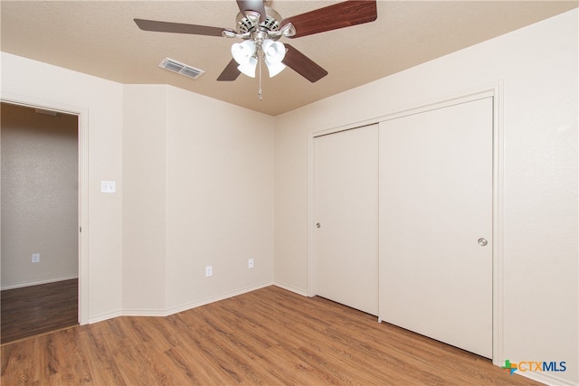 unfurnished bedroom with a closet, hardwood / wood-style flooring, and ceiling fan