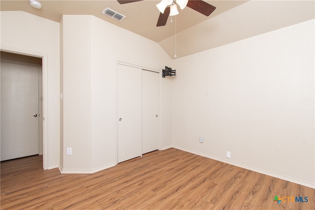 unfurnished bedroom featuring light hardwood / wood-style floors, ceiling fan, a closet, and lofted ceiling