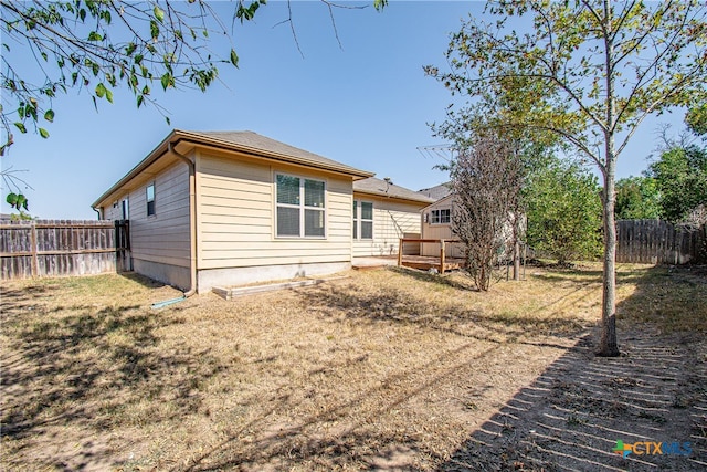 back of house with a deck and a yard