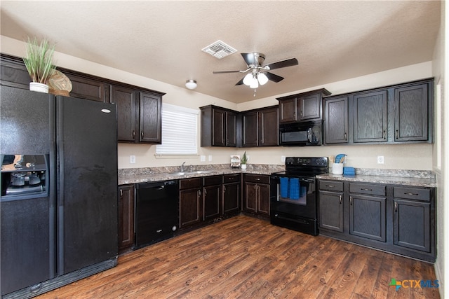 kitchen with dark wood-type flooring, black appliances, sink, ceiling fan, and light stone countertops