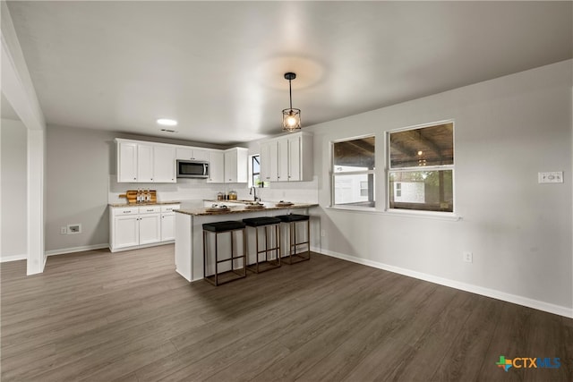 kitchen featuring dark wood-type flooring, stainless steel microwave, baseboards, and a sink