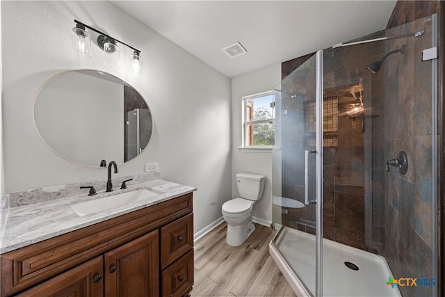 bathroom featuring toilet, wood finished floors, a stall shower, visible vents, and vanity