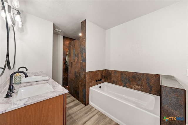 bathroom featuring double vanity, wood finished floors, a sink, a walk in shower, and a bath