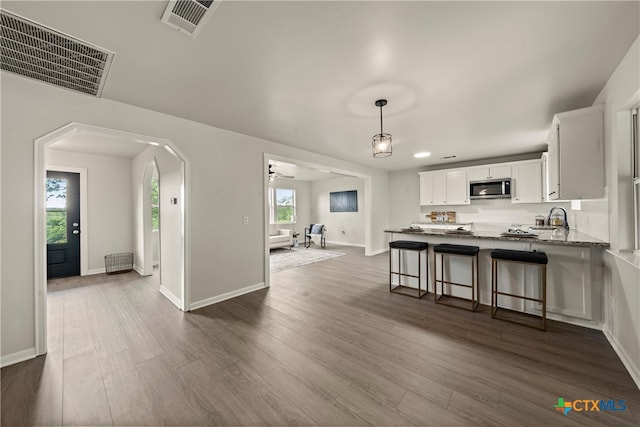 kitchen featuring dark wood-style flooring, white cabinetry, visible vents, and stainless steel microwave