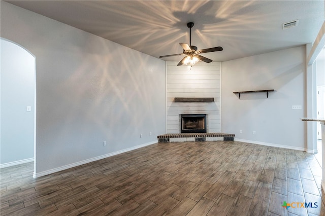 8530 Lamplight Ct, Temple, TX 76502 - unfurnished living room with a ceiling fan, wood finished floors, a large fireplace, and arched walkways