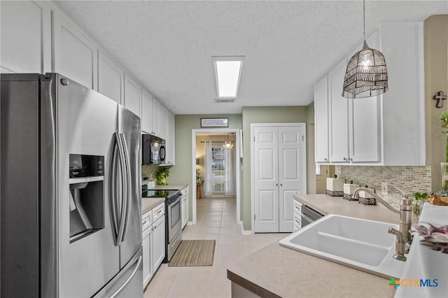 503 Ashland Crk, Victoria, TX 77901 - kitchen with stainless steel appliances, tasteful backsplash, white cabinets, light tile patterned floors, and pendant lighting