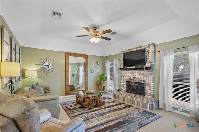 503 Ashland Crk, Victoria, TX 77901 - tiled living room featuring a brick fireplace, a tray ceiling, and ceiling fan