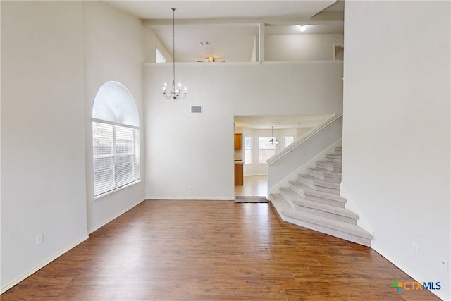 7016 Brandon Dr, Temple, TX 76502 - unfurnished living room featuring a chandelier, wood finished floors, stairway, and a towering ceiling