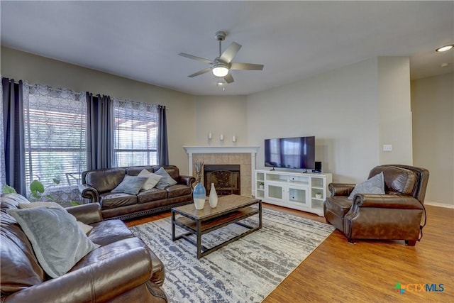 living room with baseboards, a ceiling fan, wood finished floors, and a fireplace