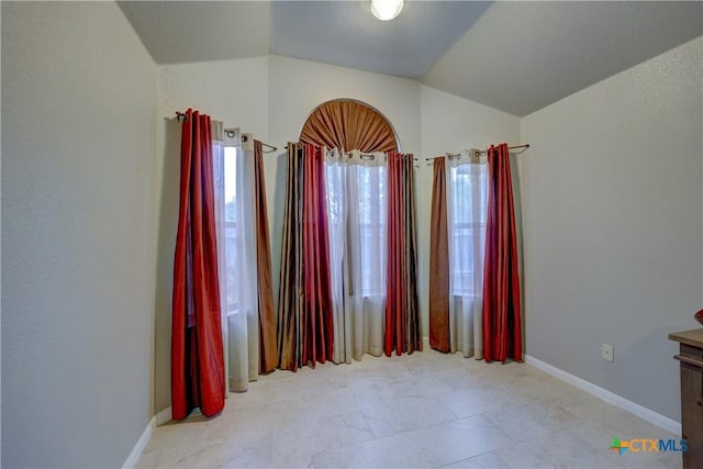 empty room with baseboards and vaulted ceiling