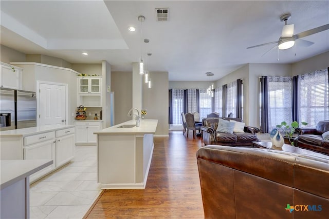 kitchen with visible vents, open floor plan, a center island with sink, stainless steel fridge, and a sink