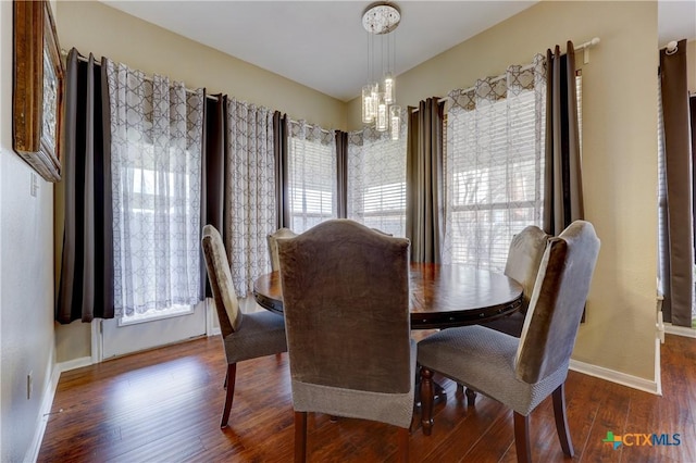 dining room featuring a chandelier, baseboards, and wood finished floors