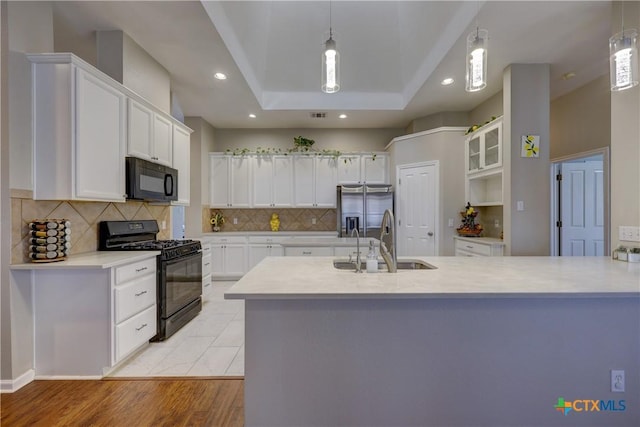 kitchen with a sink, black appliances, light countertops, and white cabinetry