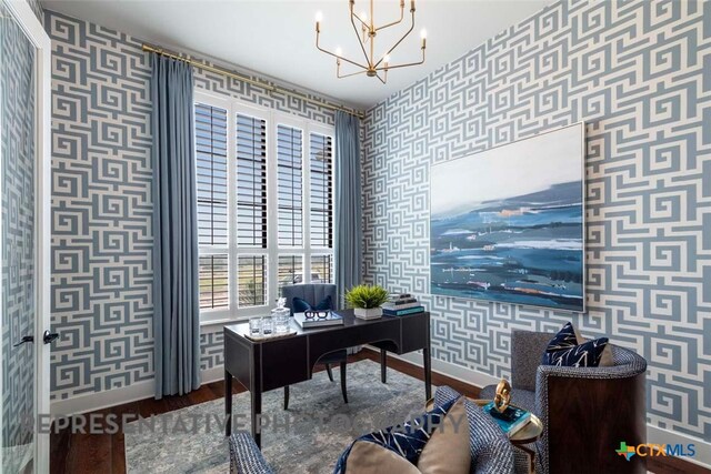 home office featuring baseboards, wallpapered walls, an inviting chandelier, and wood finished floors