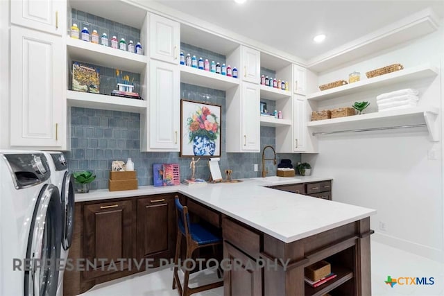 kitchen with independent washer and dryer, open shelves, a sink, white cabinets, and dark brown cabinets