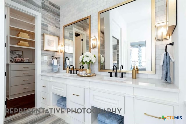 full bathroom featuring a sink, backsplash, and double vanity