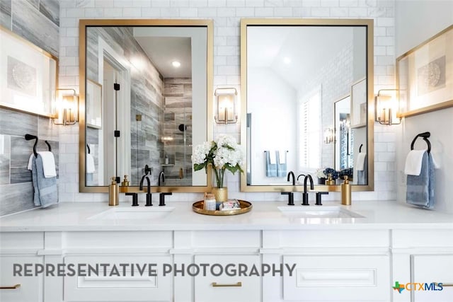 bathroom with double vanity, a shower stall, and a sink