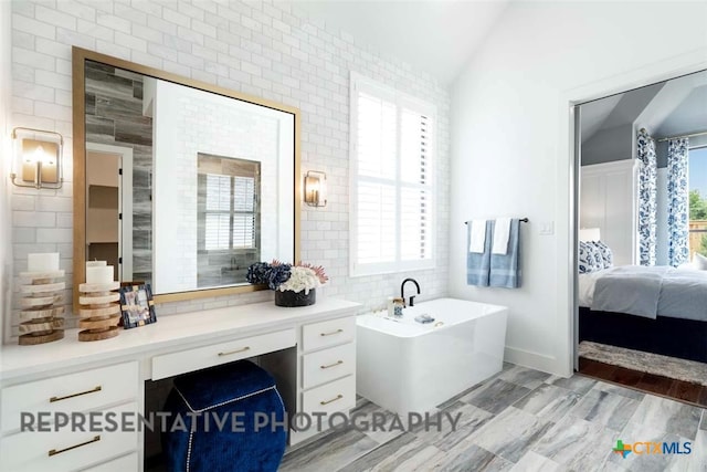 bathroom featuring vaulted ceiling, a healthy amount of sunlight, ensuite bath, and a freestanding tub