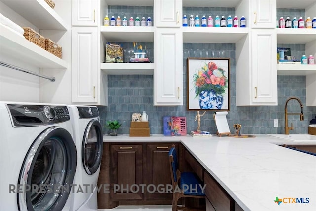 clothes washing area featuring a sink, cabinet space, and independent washer and dryer