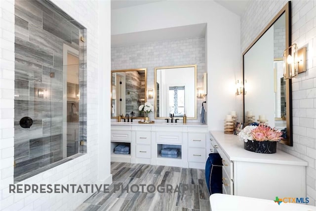 full bath featuring tiled shower, wood finished floors, and vanity