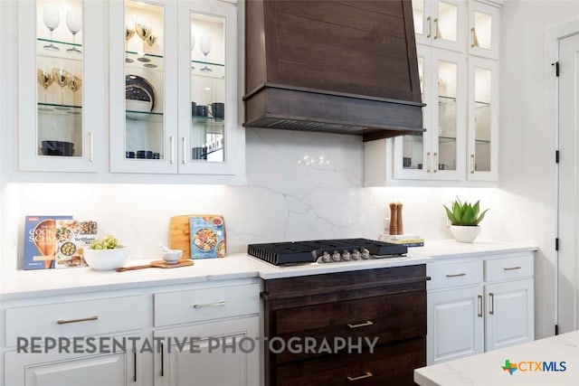 kitchen featuring custom exhaust hood, white cabinets, light countertops, and backsplash