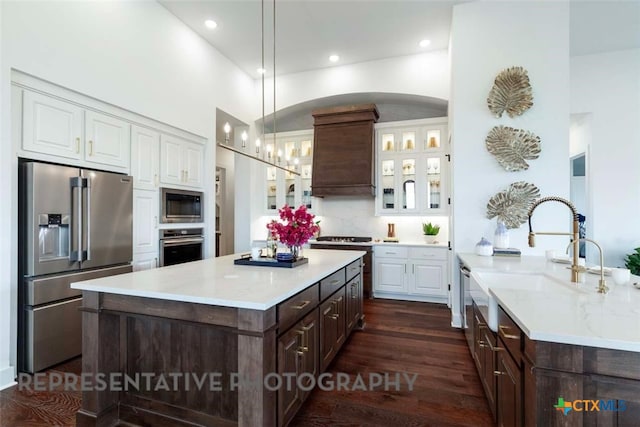 kitchen with white cabinetry, custom range hood, dark brown cabinets, and stainless steel appliances