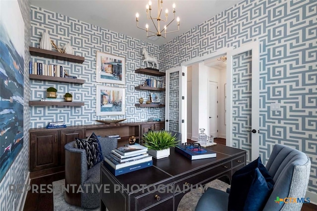 home office with baseboards, a notable chandelier, an accent wall, and wallpapered walls