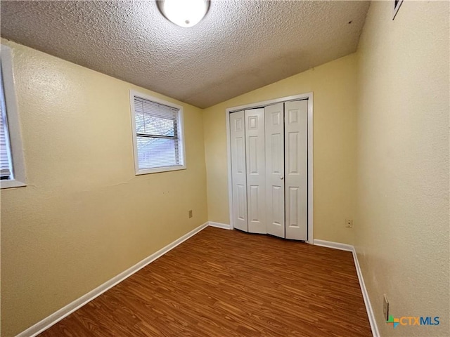 899/901 Hillyer St, San Marcos, TX 78666 - unfurnished bedroom featuring vaulted ceiling, dark wood-type flooring, baseboards, a textured ceiling, and a closet