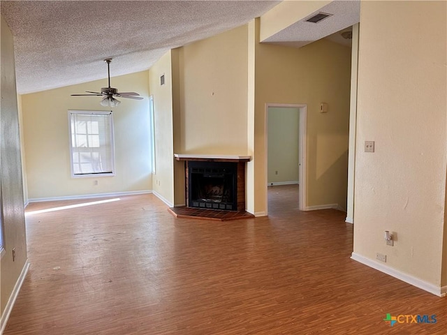 899/901 Hillyer St, San Marcos, TX 78666 - unfurnished living room featuring vaulted ceiling, wood finished floors, a textured ceiling, a fireplace with raised hearth, and baseboards