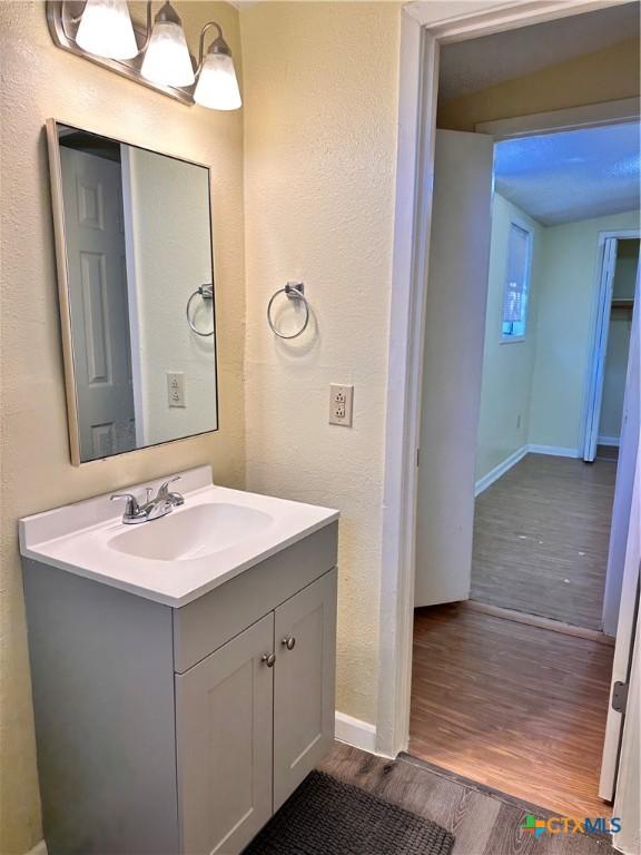 899/901 Hillyer St, San Marcos, TX 78666 - bathroom with wood finished floors, vanity, baseboards, and a textured wall