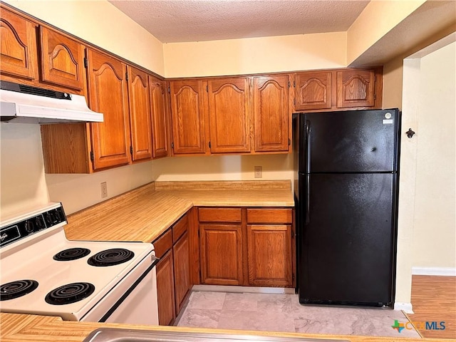 899/901 Hillyer St, San Marcos, TX 78666 - kitchen featuring freestanding refrigerator, electric range, under cabinet range hood, brown cabinetry, and light countertops